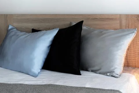 Three pillows in silk pillowcases on the bed. Stock Photos