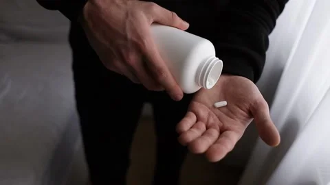 Three pills from the bottle fall into the man's hand. Stock Footage 231814177