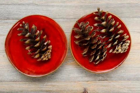 Three pine cones on a red ceramic bowl Foto stock