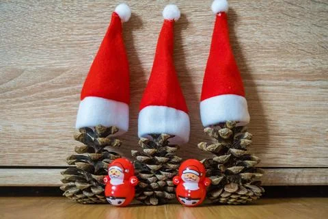 Three pine cones in a red Santa hats like a Christmas tree on wooden background Stock Photos