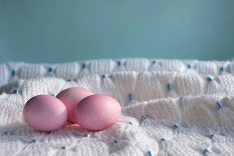 Three pink Easter eggs on a white knitted blanket Foto stock