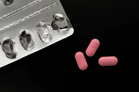 Three pink pills and empty blister pack Stock Photos