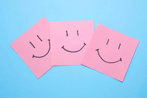Three pink sticky notes with happy smiley faces on blue background Stock Photos