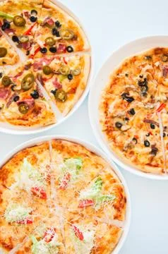 Three pizzas with different fillings on a table. Stock Photos