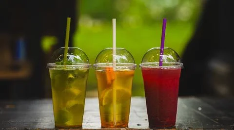 Three plastic cups with cold summer drinks with straws, lemonade with lime .. Stock Photos