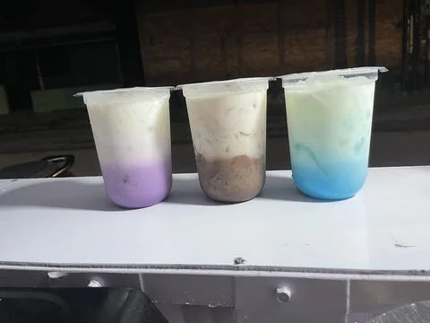 Three plastic cups hold layered smoothies Stock-Fotos