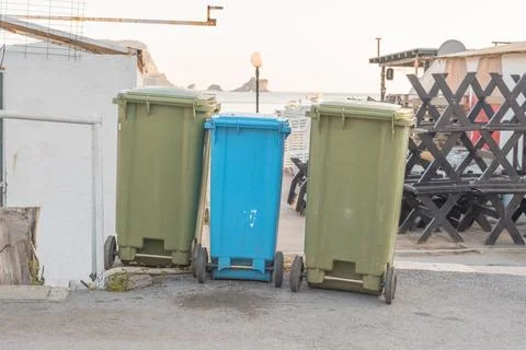 Three plastic garbage cans of different colors are on the territory of the Stock Photos