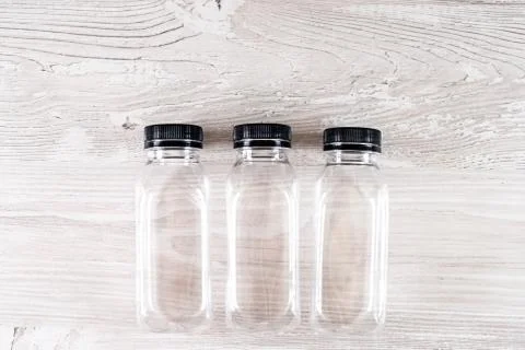 Three plastic transparent empty bottles with a black cap on a wooden table Stock Photos