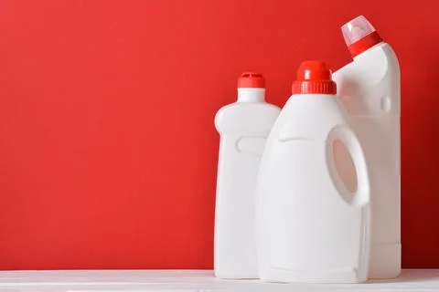 Three plastic white bottles stand on a red background. Cleaning and disinfect Stock Photos