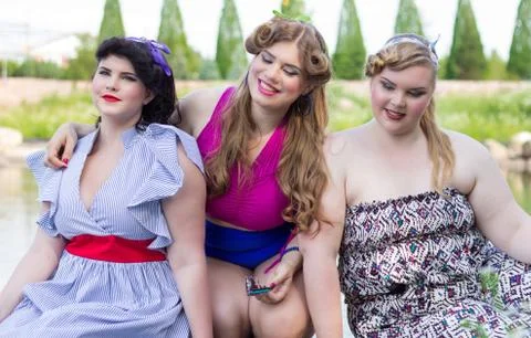 Three plus size models are sitting on the  lake Foto stock