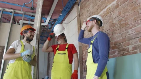 Three positive construction workers in helmet relaxing and chatting during short Stock Footage 133640521