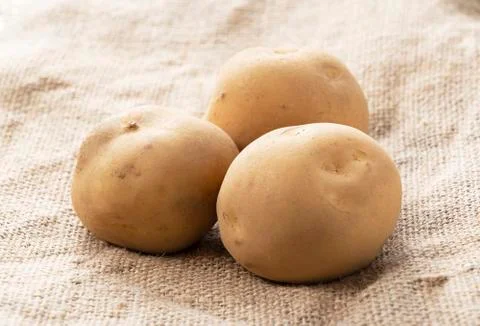 Three potatoes on a burlap Stock Photos