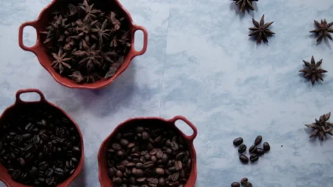Three pots of roasted coffee beans and star anise seeds on white surface Stock Footage 162555476