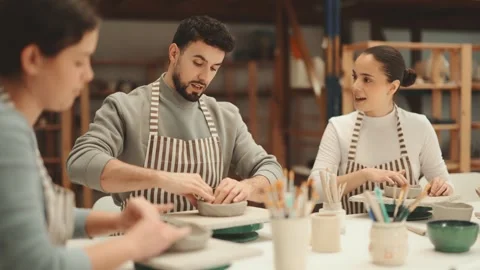 Three pottery workshop workers sculpt from raw clay, form final product Stock Footage 344773954