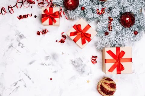 Three present boxes and snow fir tree on white concrete background. Stock Photos
