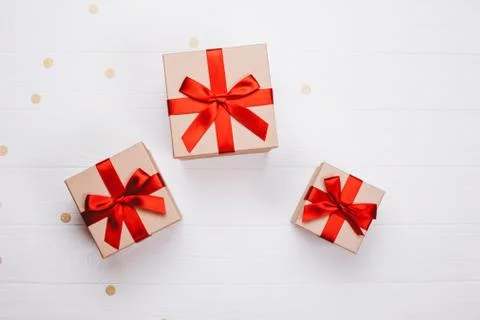 Three present boxes with red bow on wooden background. Stock Photos