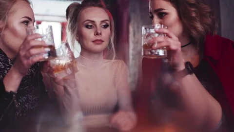 Three pretty girls having a conversation, laughing and drinking alcohol Stock Footage 74007548