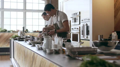 Three professional chefs cooking and preparing food on a large countertop, in in Stock Footage 199456095