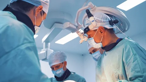 Three professional doctors in masks and medical uniform are doing an operation. Stock Footage 111425417
