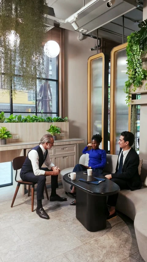 Three professionals collaborate in a modern office lounge around a coffee table 動画素材 315675228