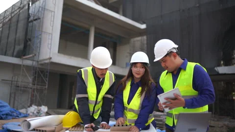 Three professionals discuss project plans at a busy construction site empha.. Stock Footage 333579737