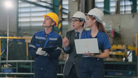 Three professionals stand in an industrial facility Stockbeeldmateriaal 345135546