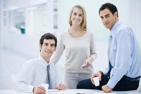 Three professionals taking a coffee break, smiling at camera Stock Photos