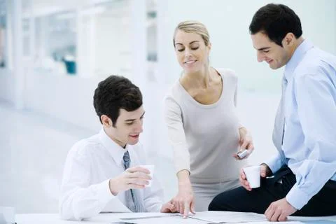 Three professionals taking a coffee break, woman pointing at newspaper 스톡 사진