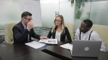 Three professionals work in office with image of bitcoin indoors. Stock Footage 85492850