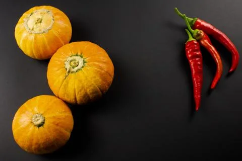 Three pumpkins, capsicum on a black background Stock Photos