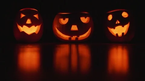 Three pumpkins glow in the night on halloween background Stock Footage
