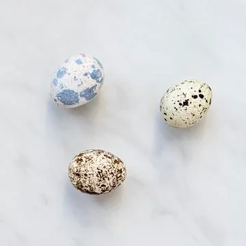 Three quail eggs on a marble surface Foto stock
