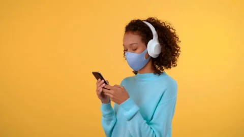 Three-quarter portrait. An Afro-haired woman wearing large white headphones and Stock Footage 141865294