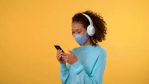 Three-quarter portrait. An Afro-haired woman wearing large white headphones and Stock Footage 141865408