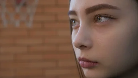 Three-quarter sad face of a beautiful girl, closes and opens her eyes, slow moti Stockbeeldmateriaal 114337986