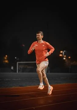 Three quarter view of a runner on a red track with goal posts behind Фото