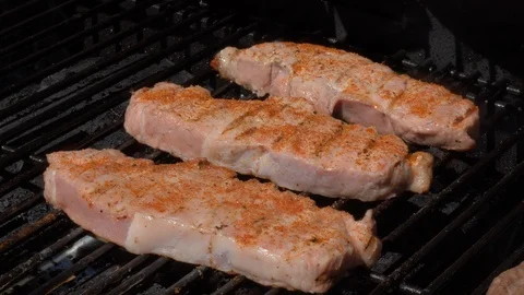 Three raw and uncooked pork chops on bbq grill Video stock 90291882