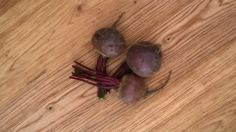 Three raw beetroot on a table, slowly rotating. Stock Footage 113217153