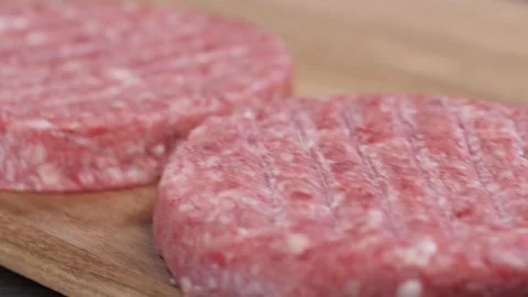 Three raw burger patties lying on a wooden board. Stock-Footage 222616970