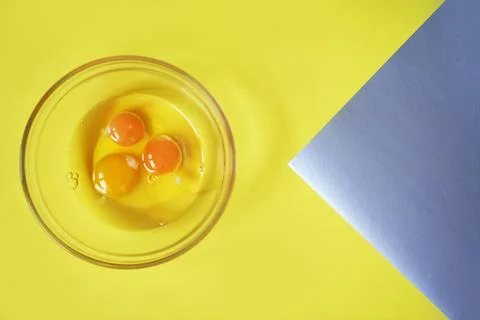 Three raw eggs on a yellow background with a silver insert and a space for Stock Photos