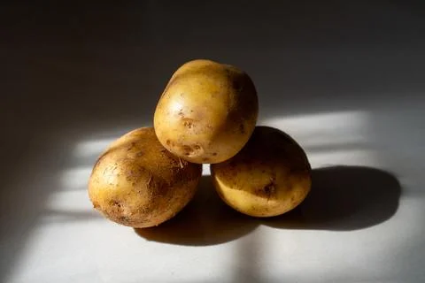 Three Raw Potatoes on White Surface Stock Photos