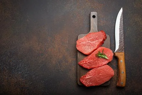 Three raw uncooked meat beef top sirloin steaks on wooden cutting board with Stock Photos