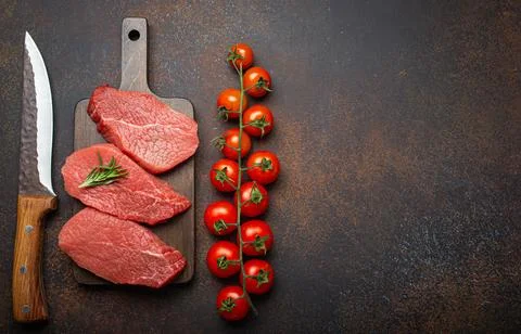 Three raw uncooked meat beef top sirloin steaks on wooden cutting board with Stock Photos