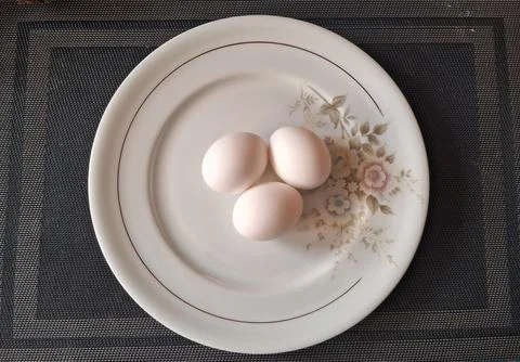 Three raw white eggs on a decorative plate. Fresh organic chicken eggs for 写真素材