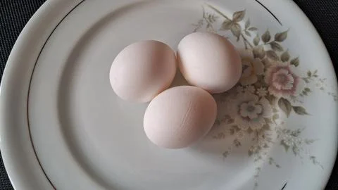 Three raw white eggs on a plate. Fresh organic chicken eggs for cooking and Stock Photos