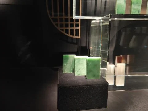 Three rectangular jade stones are placed on a black cube, surrounded by gla.. 스톡 사진