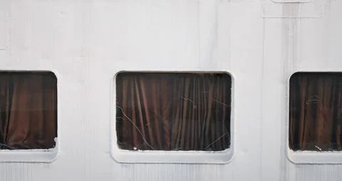 Three rectangular windows with brown curtains on a white wall surface 스톡 사진