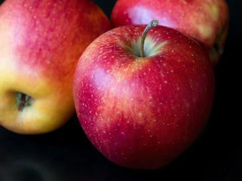 Three red apples on a black background, close-up Stock Photos