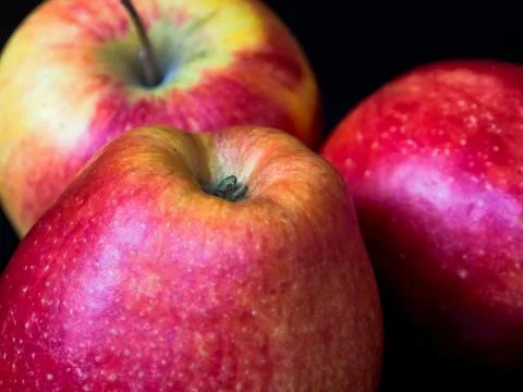 Three red apples on a black background, close-up, detail Stock Photos
