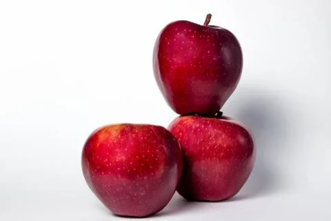 Three red apples on a white background. One apple lies on another apple.  Stock Photos